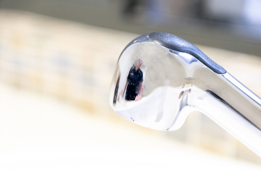 Chrome kitchen tap spout photographed close up above a pale benchtop