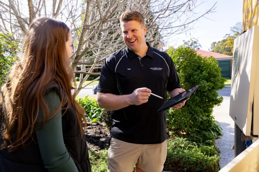 Plumber talking a homeowner through a job at the front of the house