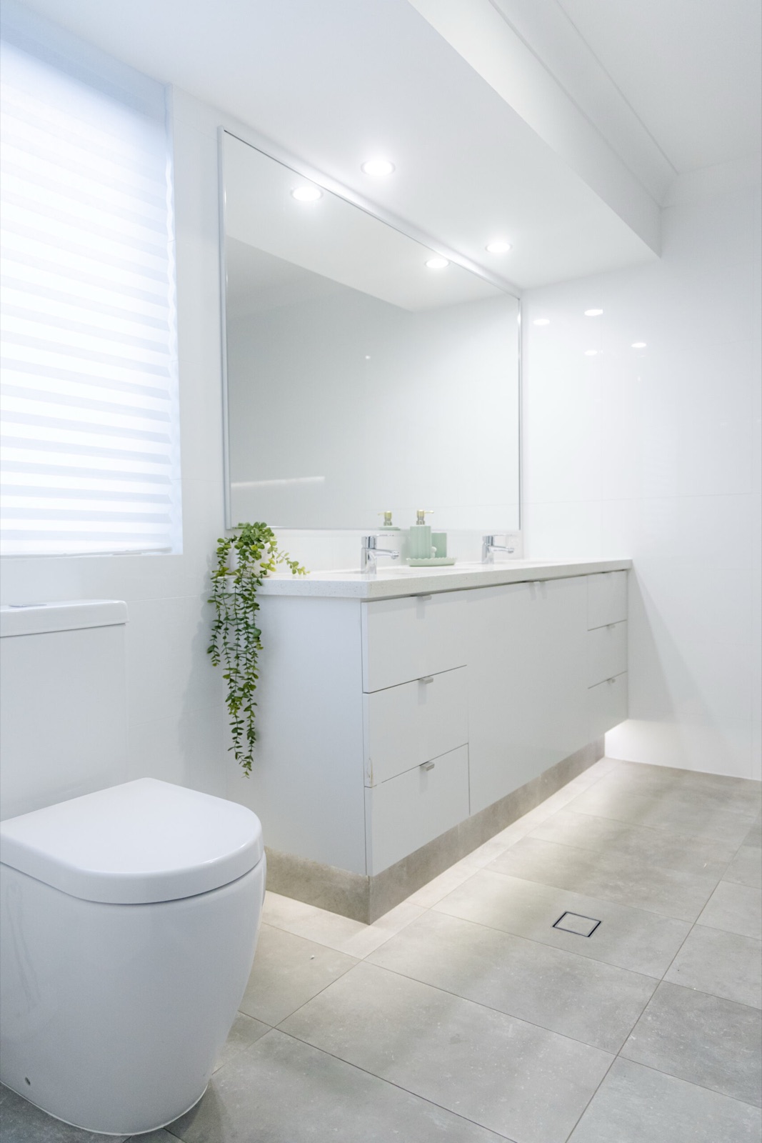 Bright white bathroom with a wall-hung vanity, twin basins and a large mirror
